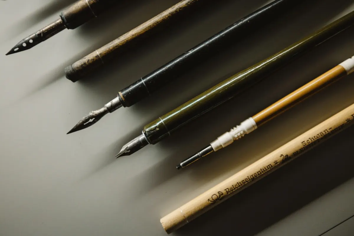 Vintage fountain pens and calligraphy nibs laid on a desk